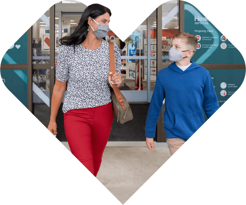 Mother and son walking out of clinic wearing masks